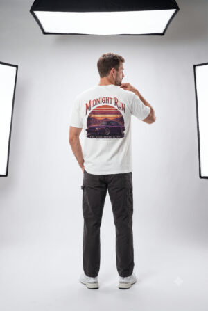 Person wearing a Midnight Run graphic t-shirt featuring a retro-inspired neon cityscape, classic late-night driving artwork, vibrant 90s color palette, and bold vintage typography, photographed in a professional studio.