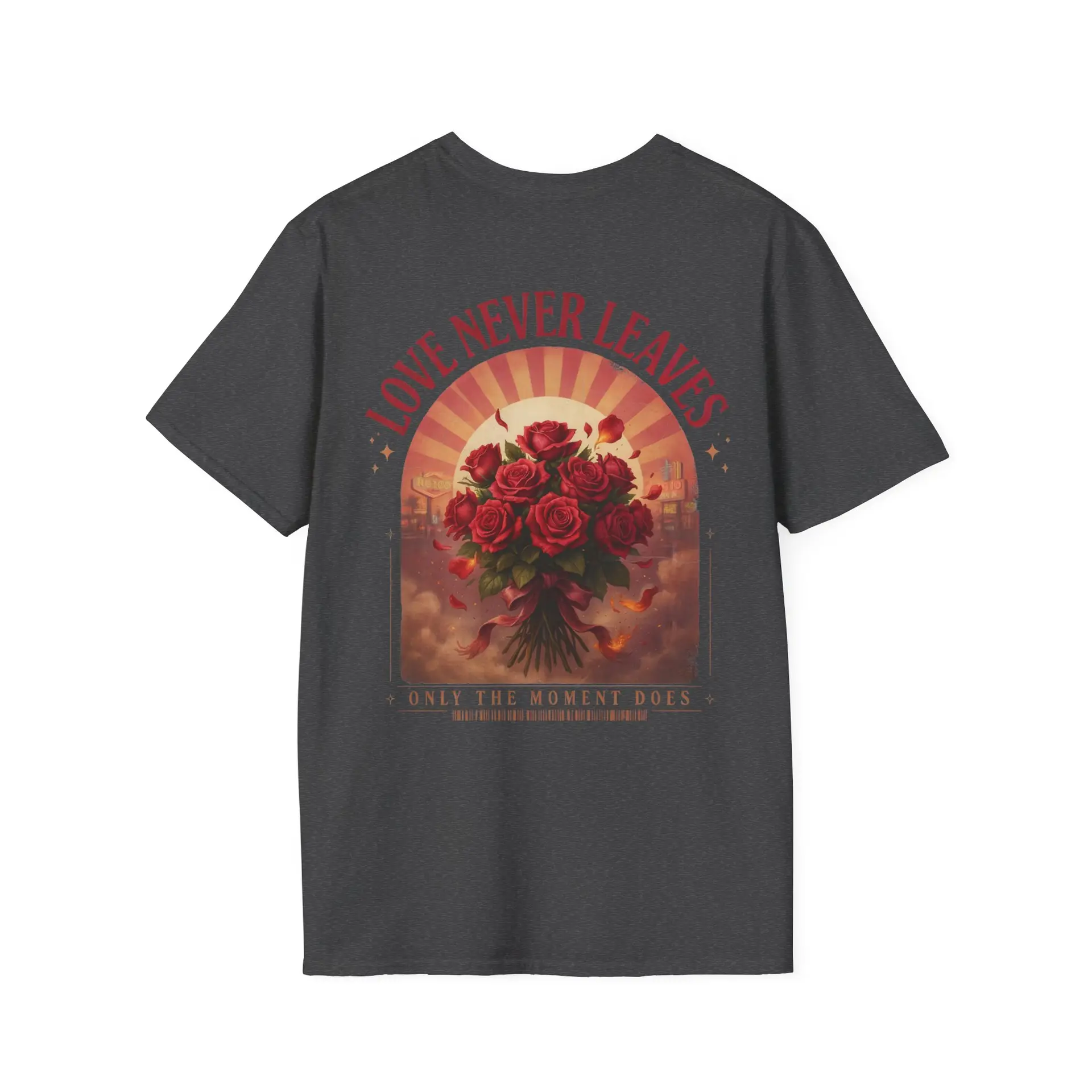 Person wearing a Love Never Leaves graphic t-shirt featuring a vintage-inspired bouquet of deep red roses, warm sunset tones, scattered rose petals, and elegant typography reading "Love Never Leaves" and "Only The Moment Does," photographed in a professional studio.
