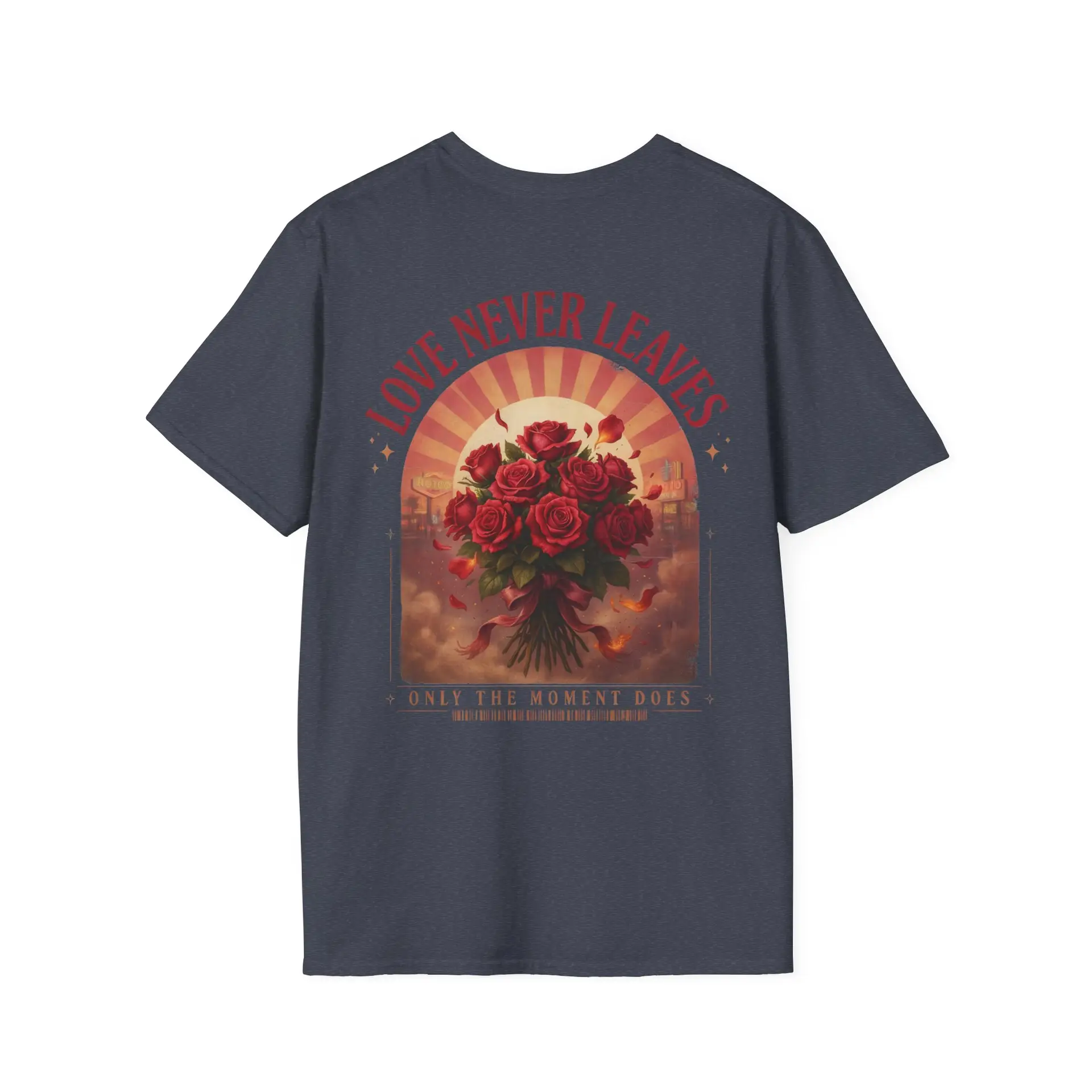 Person wearing a Love Never Leaves graphic t-shirt featuring a vintage-inspired bouquet of deep red roses, warm sunset tones, scattered rose petals, and elegant typography reading "Love Never Leaves" and "Only The Moment Does," photographed in a professional studio.
