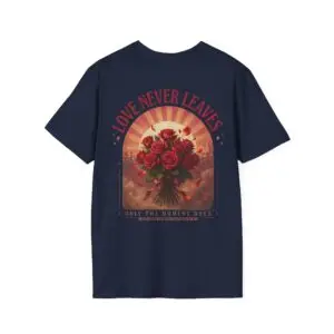 Person wearing a Love Never Leaves graphic t-shirt featuring a vintage-inspired bouquet of deep red roses, warm sunset tones, scattered rose petals, and elegant typography reading "Love Never Leaves" and "Only The Moment Does," photographed in a professional studio.