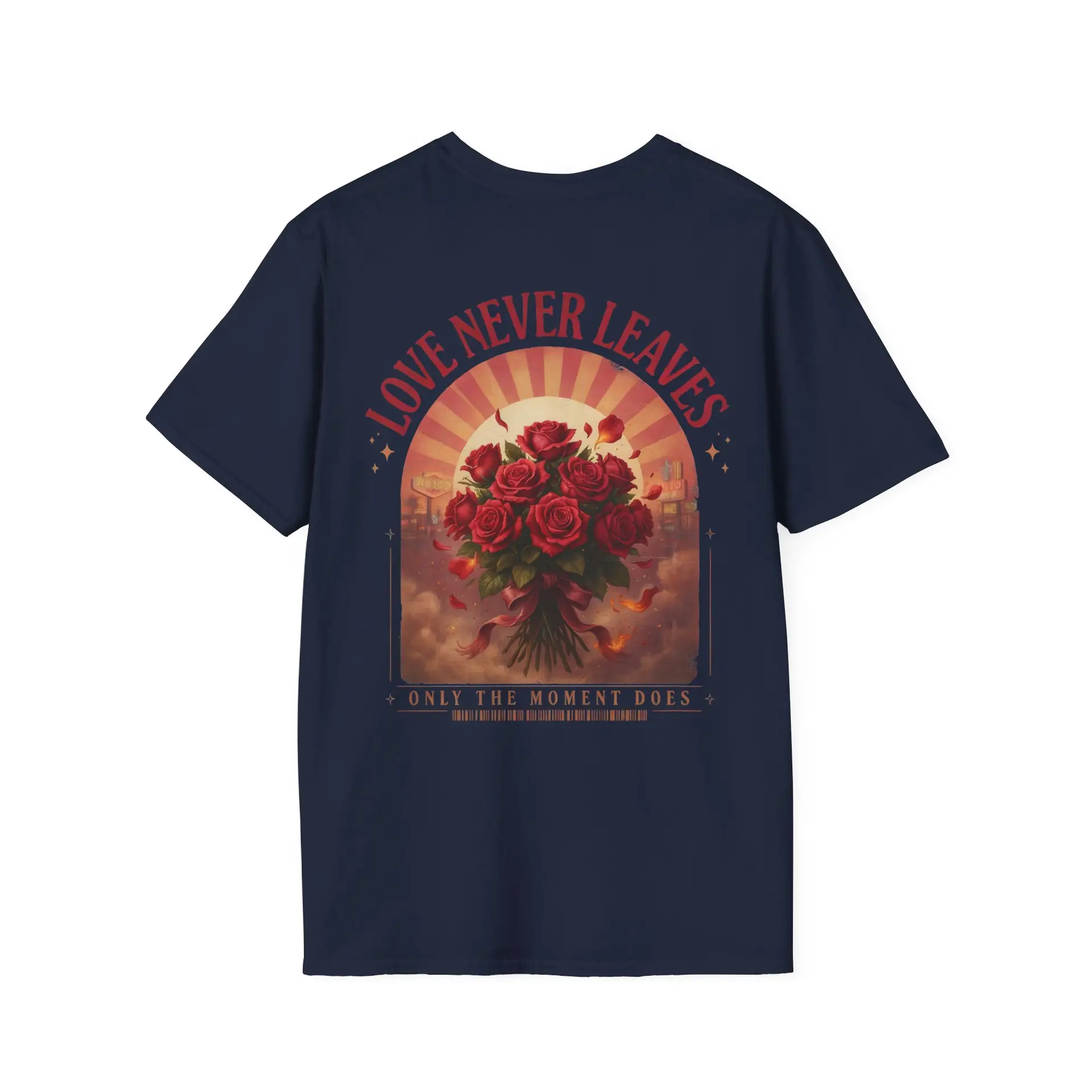 Person wearing a Love Never Leaves graphic t-shirt featuring a vintage-inspired bouquet of deep red roses, warm sunset tones, scattered rose petals, and elegant typography reading "Love Never Leaves" and "Only The Moment Does," photographed in a professional studio.
