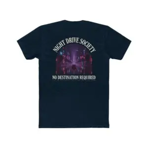 Person wearing a Night Drive Society graphic t-shirt featuring a retro-futuristic neon city skyline, rain-soaked streets, towering palm trees, and a classic car driving into the night with bold typography reading "No Destination Required" and "Lost In The Lights • Built For The After Hours," photographed in a professional studio.