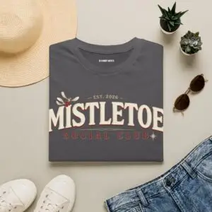 Woman wearing a black Mistletoe Social Club Christmas graphic t-shirt featuring vintage holiday typography with festive mistletoe accents