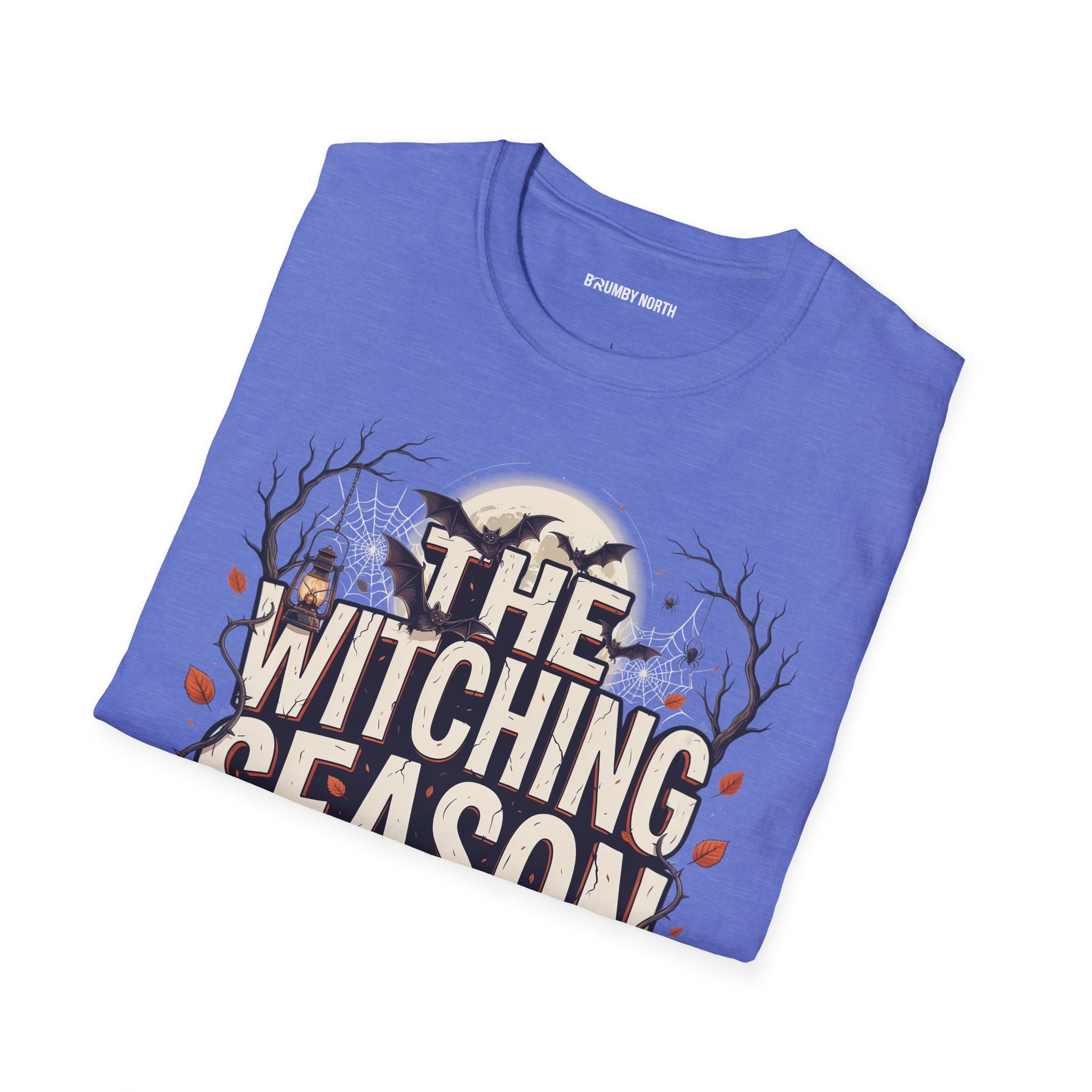 Woman wearing a blue The Witching Season Halloween graphic t-shirt featuring vintage spooky typography, a smiling jack-o'-lantern, moon, and autumn tree silhouettes in a professional studio.