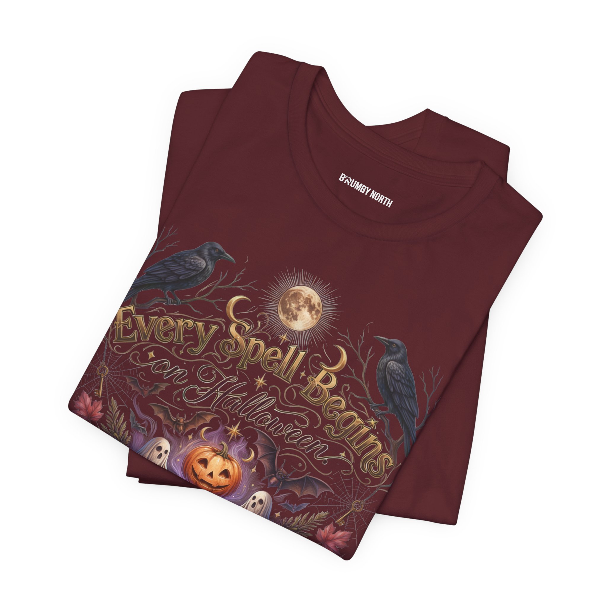 Woman wearing a black Bella+Canvas Halloween graphic t-shirt featuring a vintage illustration of an enchanted spell book, pumpkin, ghosts, candles, ravens, and the phrase "Every Spell Begins on Halloween."