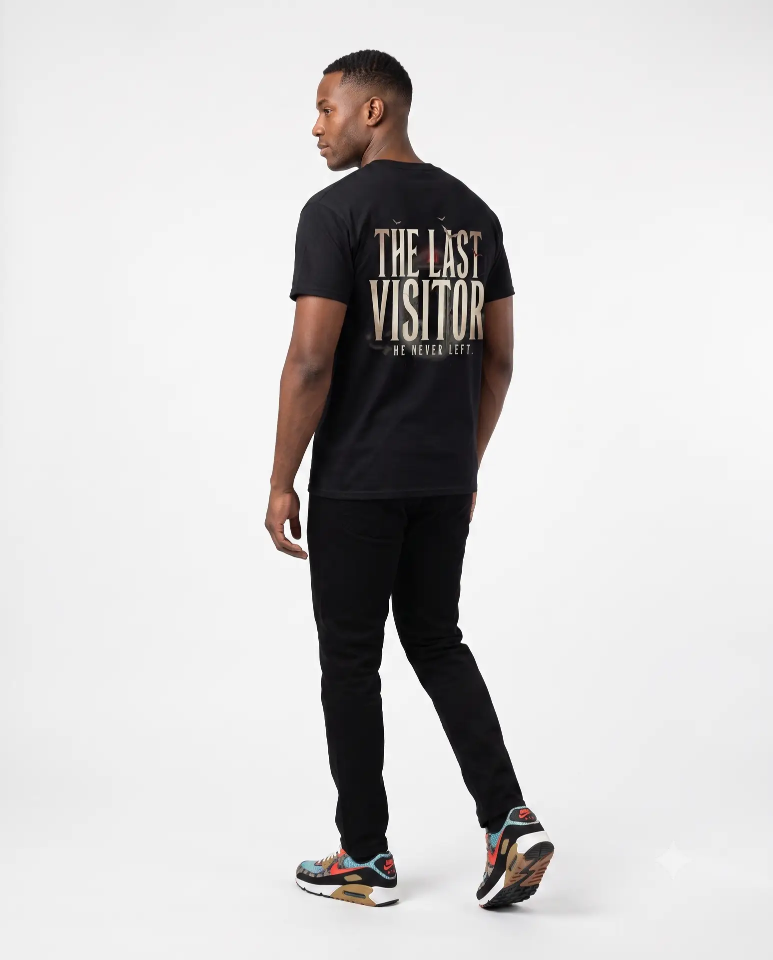 Image Alt Text (Front) Black Bella+Canvas 3001 unisex t-shirt featuring a vintage gothic "Visitor" front graphic with minimalist horror typography, modeled in a studio setting. Image Alt Text (Back) Back view of a black Bella+Canvas 3001 unisex t-shirt featuring "The Last Visitor" gothic horror back graphic with vintage typography and subtle distressed details, modeled in a studio setting.