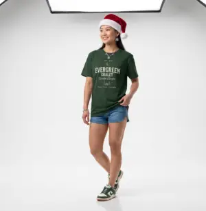Evergreen Chalet Winter Escape Christmas graphic T-shirt on female model Forest green vintage Christmas cabin graphic tee front view Cozy winter lodge inspired unisex holiday T-shirt Evergreen Chalet Christmas shirt premium cotton graphic tee