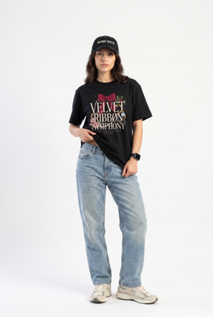 Woman wearing a black Velvet Ribbon Symphony Christmas graphic t-shirt featuring elegant holiday typography with a festive velvet ribbon, floral accents, and winter-inspired artwork.