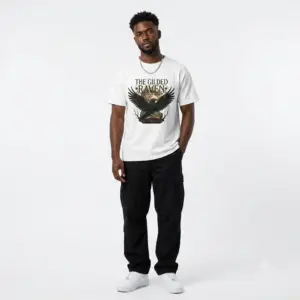 Person wearing a The Gilded Raven graphic t-shirt featuring a minimalist raven positioned before a glowing full moon with bold vintage-inspired typography reading "The Gilded Raven," photographed in a professional studio.