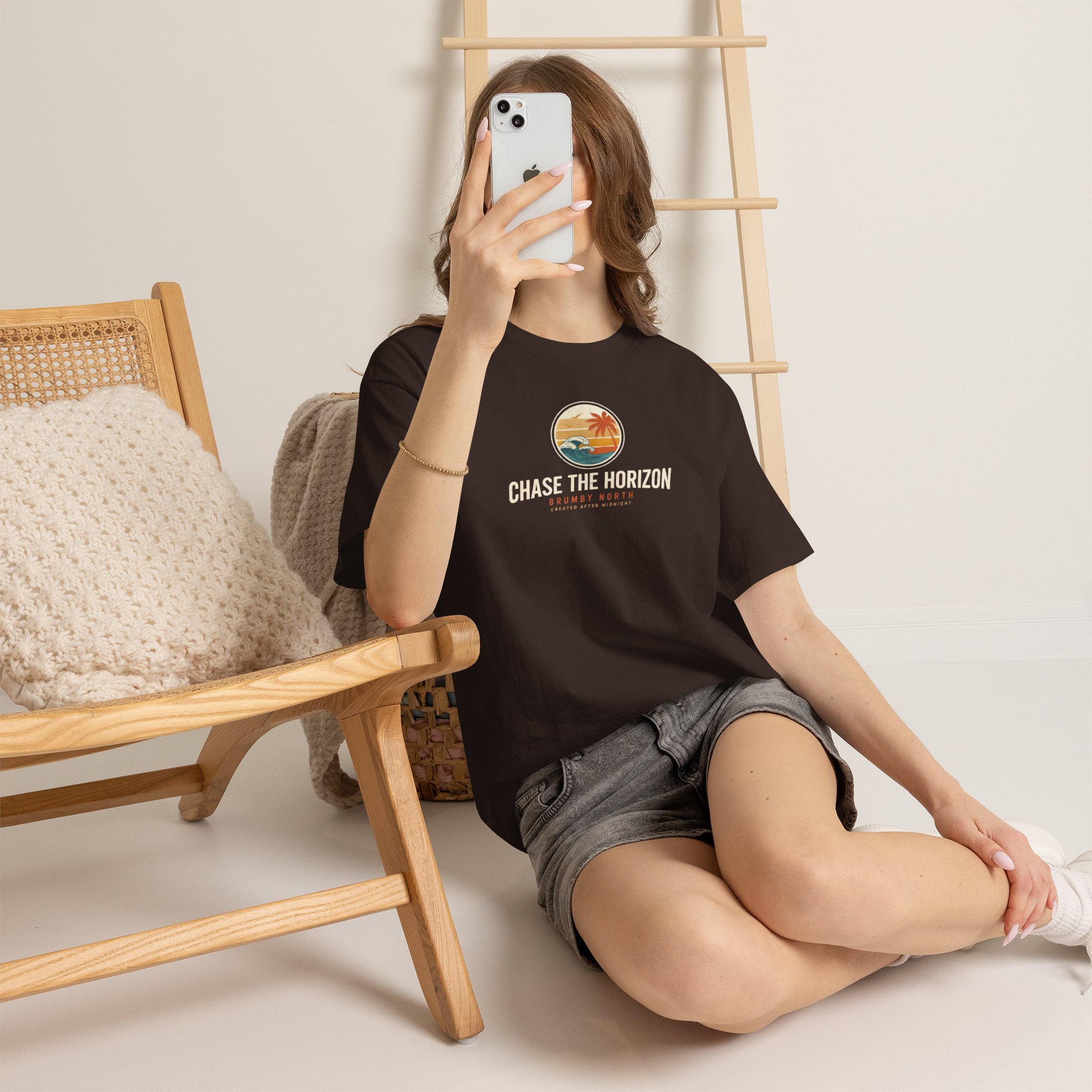 Front Image Woman wearing an olive green Chase The Horizon vintage surf graphic unisex heavy cotton t-shirt featuring a retro sunset chest print in a professional studio. Back Image Back view of woman wearing an olive green Chase The Horizon vintage surf graphic t-shirt with a large retro ocean wave and sunset illustration in a studio setting