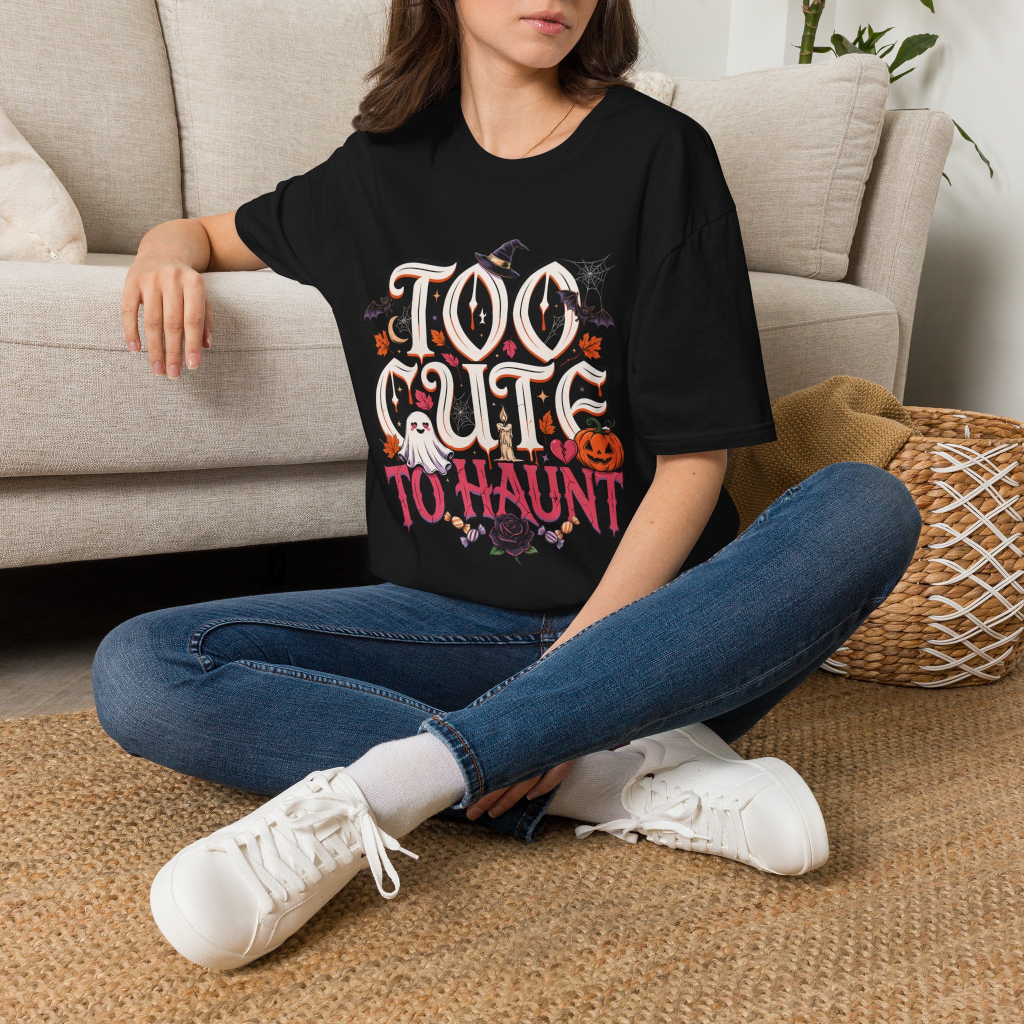 Woman wearing a black Too Cute To Haunt Halloween graphic t-shirt featuring vintage typography, a cute ghost, pumpkin, autumn leaves, and spooky accents in a professional studio.