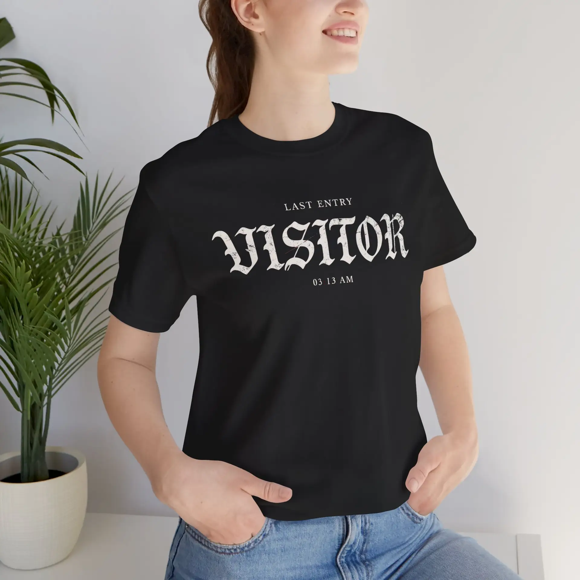 Image Alt Text (Front) Black Bella+Canvas 3001 unisex t-shirt featuring a vintage gothic "Visitor" front graphic with minimalist horror typography, modeled in a studio setting. Image Alt Text (Back) Back view of a black Bella+Canvas 3001 unisex t-shirt featuring "The Last Visitor" gothic horror back graphic with vintage typography and subtle distressed details, modeled in a studio setting.