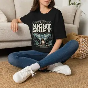 Woman wearing a red Night Shift vintage moth graphic unisex t-shirt with gothic typography and pocket watch illustration on a white studio background.