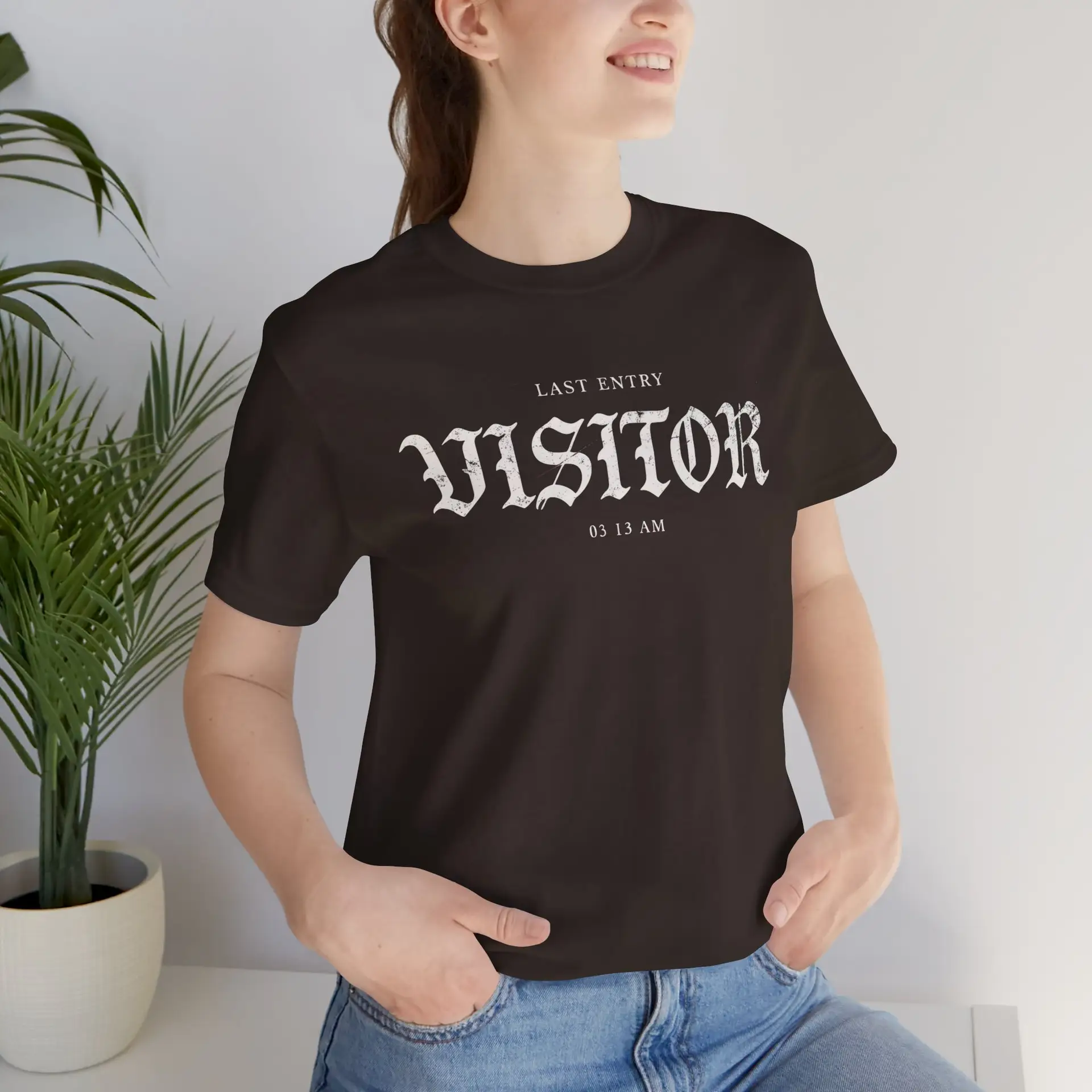 Image Alt Text (Front) Black Bella+Canvas 3001 unisex t-shirt featuring a vintage gothic "Visitor" front graphic with minimalist horror typography, modeled in a studio setting. Image Alt Text (Back) Back view of a black Bella+Canvas 3001 unisex t-shirt featuring "The Last Visitor" gothic horror back graphic with vintage typography and subtle distressed details, modeled in a studio setting.