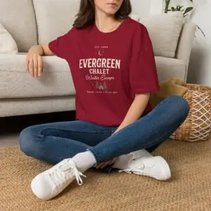 Evergreen Chalet Winter Escape Christmas graphic T-shirt on female model Forest green vintage Christmas cabin graphic tee front view Cozy winter lodge inspired unisex holiday T-shirt Evergreen Chalet Christmas shirt premium cotton graphic tee