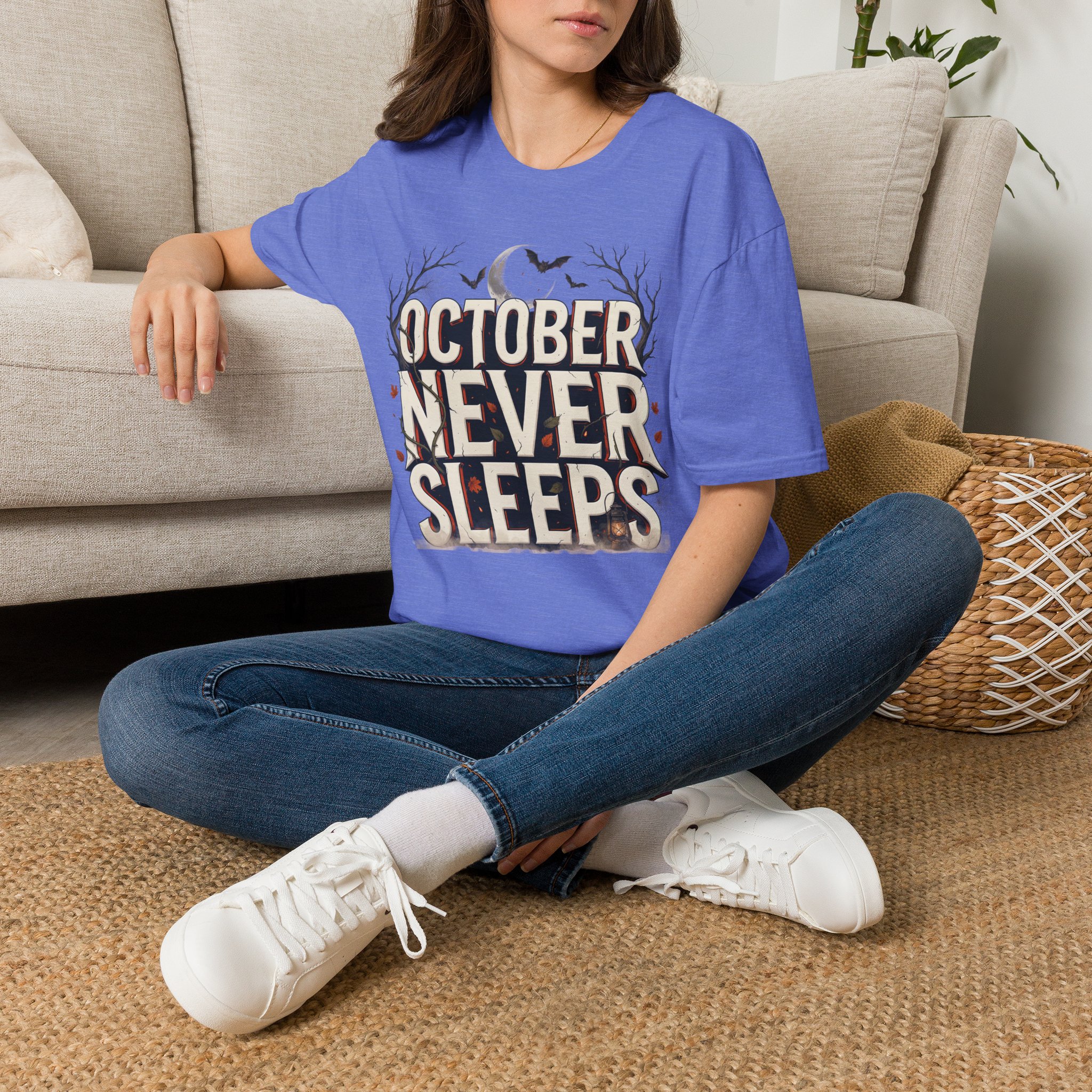 Woman wearing a purple October Never Sleeps Halloween graphic t-shirt featuring a vintage spooky typography design with moon, bats, and autumn tree silhouettes in a professional studio.