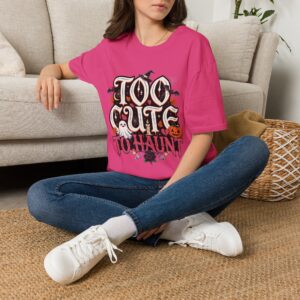 Woman wearing a black Too Cute To Haunt Halloween graphic t-shirt featuring vintage typography, a cute ghost, pumpkin, autumn leaves, and spooky accents in a professional studio.