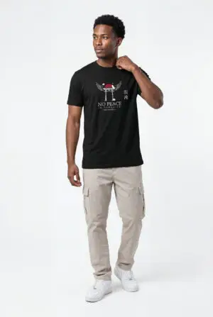 Person wearing a black No Peace In Paradise graphic t-shirt featuring a hooded figure with angel wings beneath a traditional Japanese torii gate, set against a crimson moon with ravens, floral elements, and gothic typography reading "Built From Chaos" and "Everything Beautiful Comes From Damage," photographed in a professional studio.