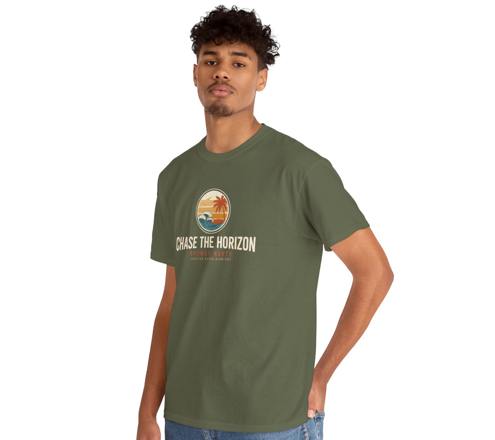Woman wearing an olive green Chase The Horizon vintage surf graphic unisex heavy cotton t-shirt featuring a retro sunset chest print in a professional studio. Back Image Back view of woman wearing an olive green Chase The Horizon vintage surf graphic t-shirt with a large retro ocean wave and sunset illustration in a studio setting