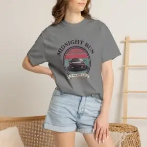 Person wearing a Midnight Run graphic t-shirt featuring a retro-inspired neon cityscape, classic late-night driving artwork, vibrant 90s color palette, and bold vintage typography, photographed in a professional studio.