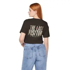 Image Alt Text (Front) Black Bella+Canvas 3001 unisex t-shirt featuring a vintage gothic "Visitor" front graphic with minimalist horror typography, modeled in a studio setting. Image Alt Text (Back) Back view of a black Bella+Canvas 3001 unisex t-shirt featuring "The Last Visitor" gothic horror back graphic with vintage typography and subtle distressed details, modeled in a studio setting.