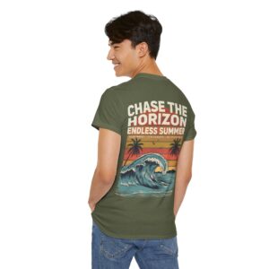 Woman wearing an olive green Chase The Horizon vintage surf graphic unisex heavy cotton t-shirt featuring a retro sunset chest print in a professional studio. Back Image Back view of woman wearing an olive green Chase The Horizon vintage surf graphic t-shirt with a large retro ocean wave and sunset illustration in a studio setting