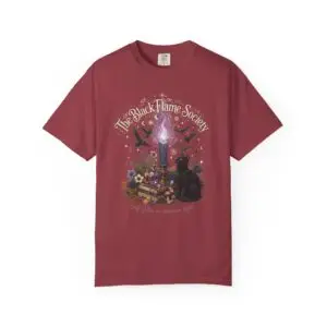 Comfort Colors 1717 black garment-dyed Halloween t-shirt featuring The Black Flame Society graphic with black cats, candles, purple flame, pumpkins, spell books, and witchy aesthetic artwork
