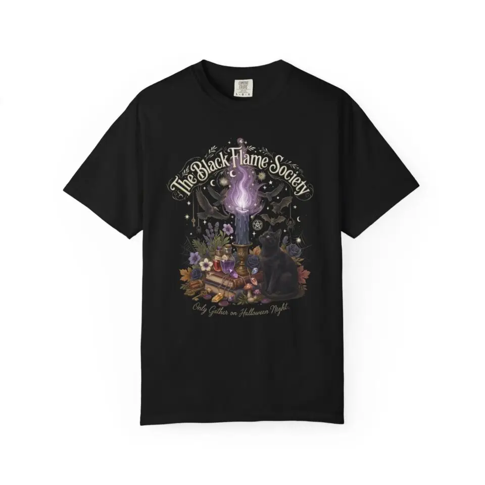 Comfort Colors 1717 black garment-dyed Halloween t-shirt featuring The Black Flame Society graphic with black cats, candles, purple flame, pumpkins, spell books, and witchy aesthetic artwork