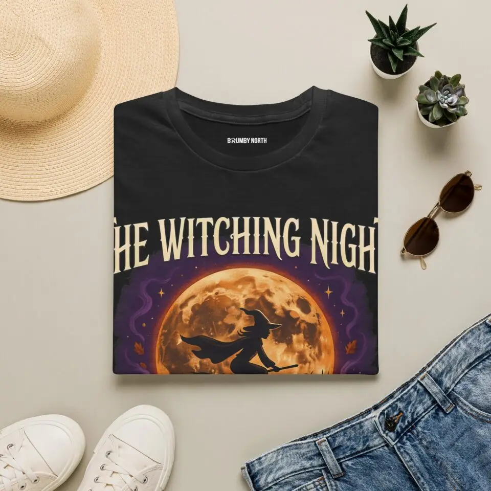 Front view of a black Gildan Softstyle 64000 unisex t-shirt featuring "The Witching Night" vintage Halloween graphic with a full moon, flying witch, and gothic typography, modeled in a studio setting.