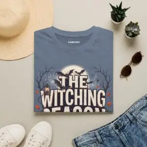 Witching Season Halloween graphic t-shirt featuring vintage spooky typography, a smiling jack-o'-lantern, moon, and autumn tree silhouettes in a professional studio.
