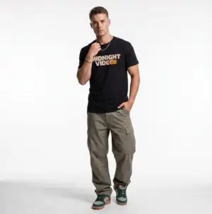 Model wearing the Midnight Video retro graphic unisex T-shirt in a studio Short Product Text Late-night video store nostalgia meets everyday streetwear. The Midnight Video T-Shirt features a retro-inspired graphic built around “MIDNIGHT VIDEO” and “RENT AFTER DARK.” SEO Keywords / Tags midnight video t-shirt, retro graphic tee, VHS t-shirt, vintage video store tee, retro streetwear, nostalgic graphic t-shirt, unisex graphic tee, retro movie shirt, casual streetwear, 90s inspired t-shirt, after dark graphic tee