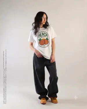 Peach Season vintage graphic T-shirt worn by a female model with relaxed black jeans in a studio setting. Shorter SEO Alt Text Peach Season vintage fruit graphic unisex T-shirt