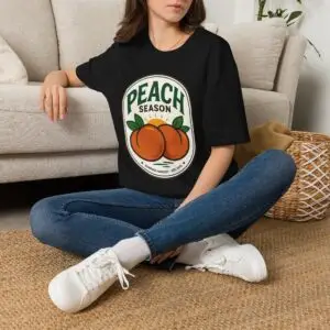 Peach Season vintage graphic T-shirt worn by a female model with relaxed black jeans in a studio setting. Shorter SEO Alt Text Peach Season vintage fruit graphic unisex T-shirt