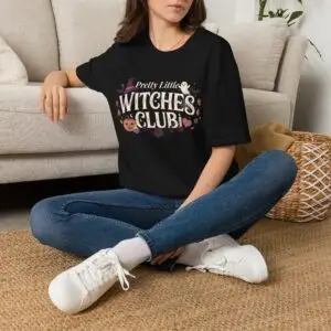 Pink Gildan Softstyle Halloween t-shirt featuring the "Pretty Little Witches Club" graphic with pumpkins, ghosts, bats, stars, and cute spooky fall artwork.