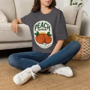 Peach Season vintage graphic T-shirt worn by a female model with relaxed black jeans in a studio setting. Shorter SEO Alt Text Peach Season vintage fruit graphic unisex T-shirt