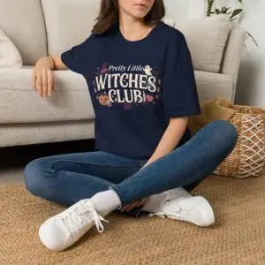 Pink Gildan Softstyle Halloween t-shirt featuring the "Pretty Little Witches Club" graphic with pumpkins, ghosts, bats, stars, and cute spooky fall artwork.