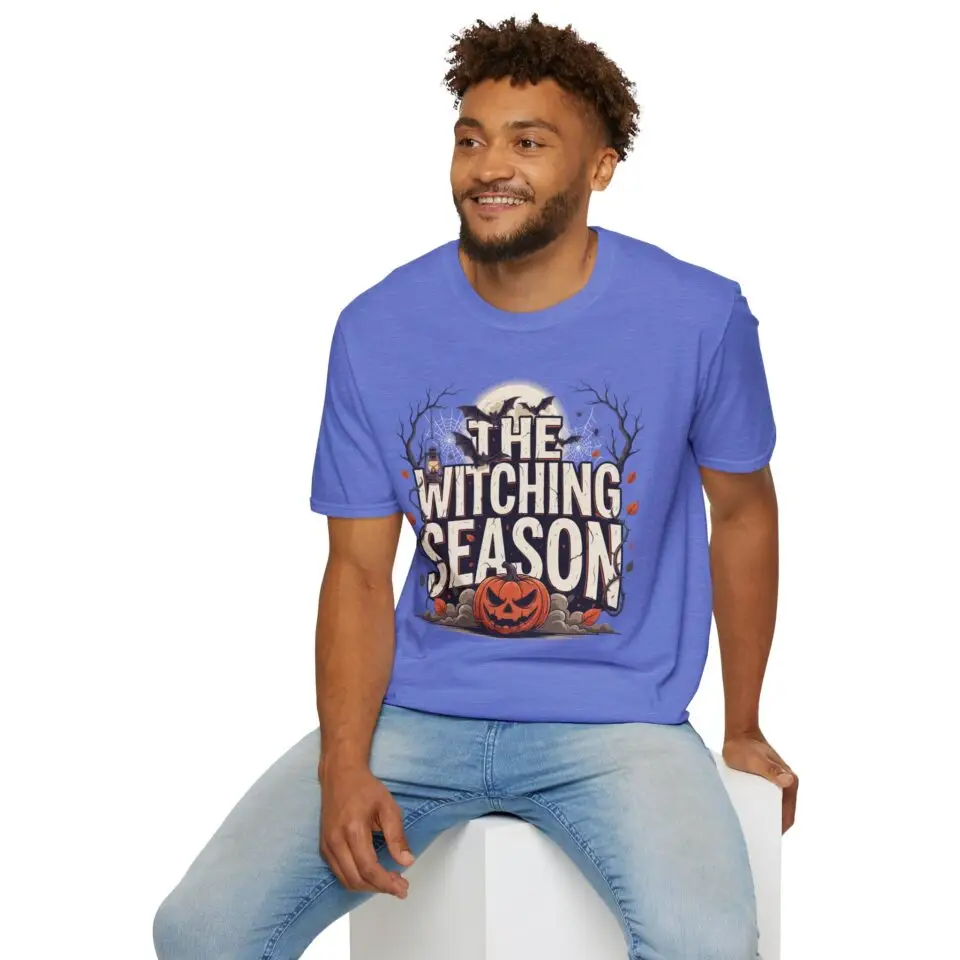 Witching Season Halloween graphic t-shirt featuring vintage spooky typography, a smiling jack-o'-lantern, moon, and autumn tree silhouettes in a professional studio.