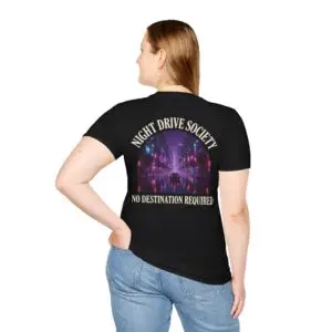 Person wearing a black Night Drive Society graphic t-shirt featuring a retro-futuristic neon city skyline, rain-soaked streets, towering palm trees, and a classic car driving into the night with bold typography reading "No Destination Required" and "Lost In The Lights • Built For The After Hours," photographed in a professional studio.