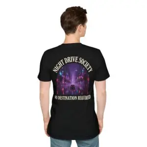 Person wearing a black Night Drive Society graphic t-shirt featuring a retro-futuristic neon city skyline, rain-soaked streets, towering palm trees, and a classic car driving into the night with bold typography reading "No Destination Required" and "Lost In The Lights • Built For The After Hours," photographed in a professional studio.